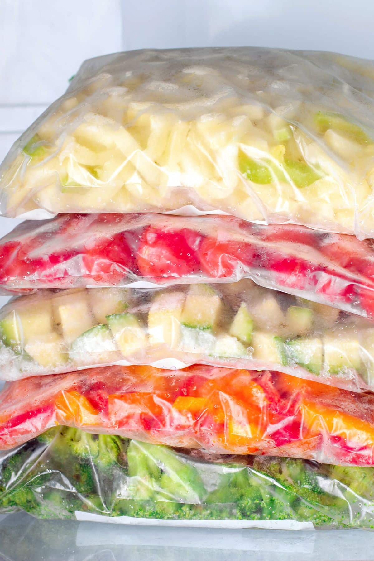 Plastic baggies of diced frozen veggies stacked in the freezer.
