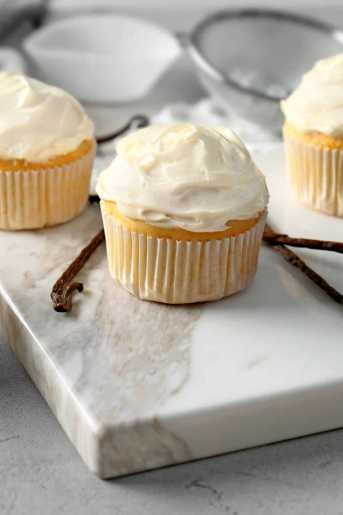 Vanilla gluten-free and dairy-free cupcakes on a white marble surface.