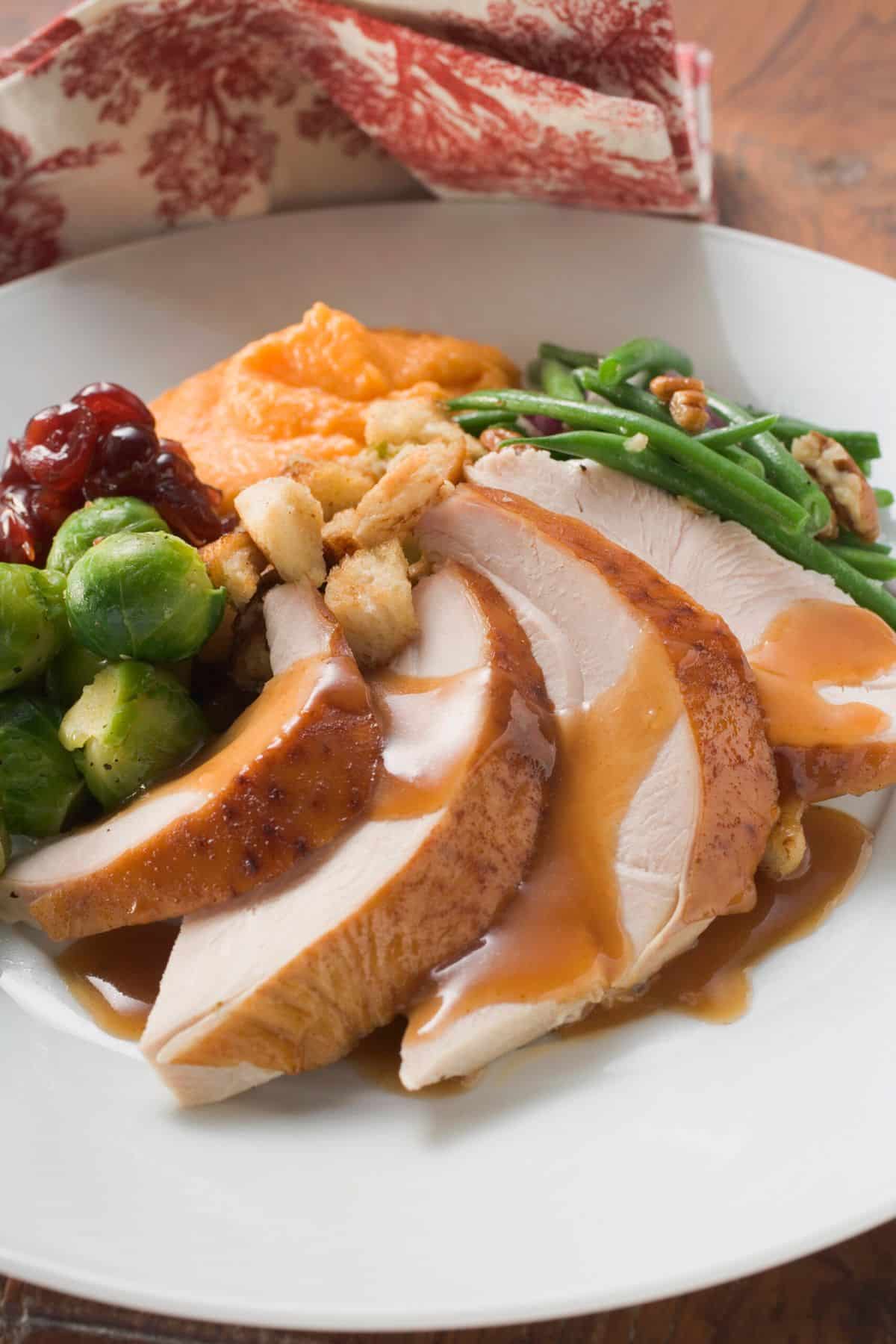 A full dinner plate of thanksgiving dinner with dairy-free gravy over turkey slices.