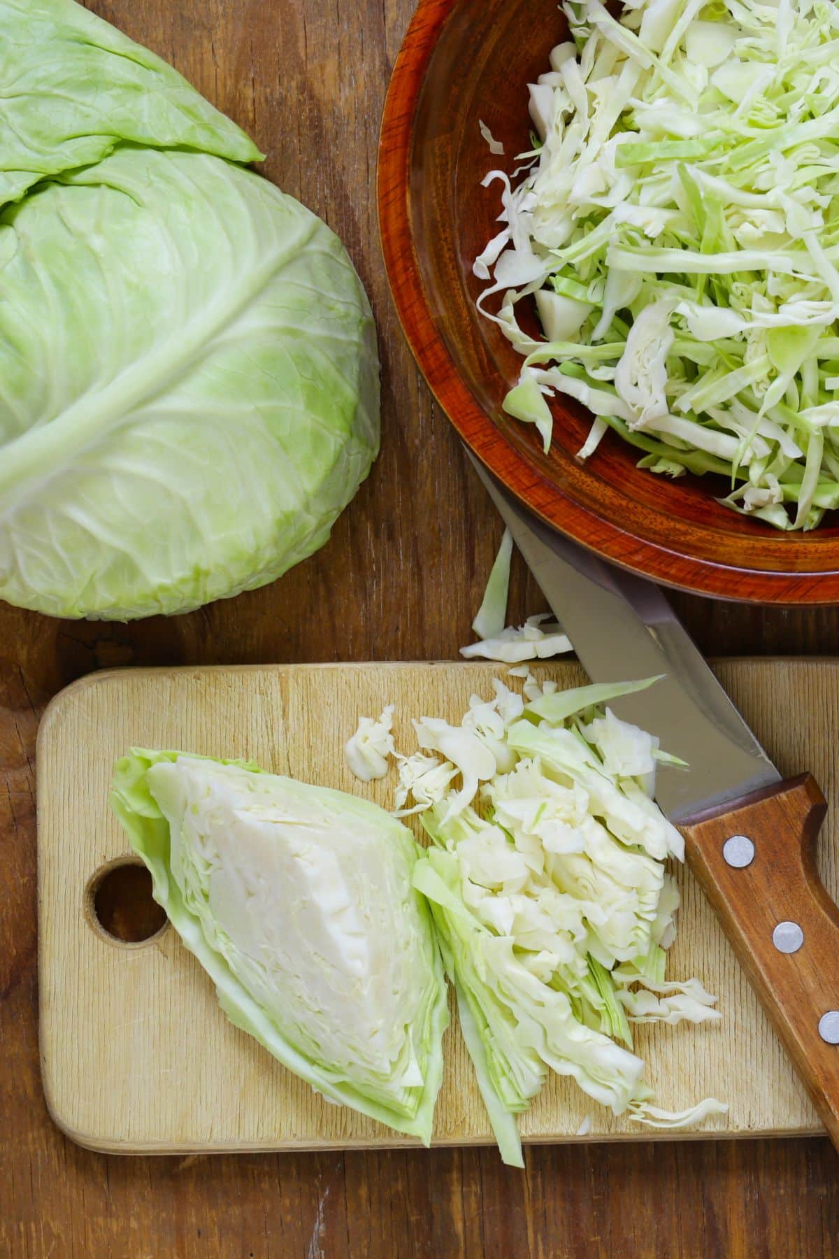 Halved and Sliced cabbage in bowl and on wooden board.