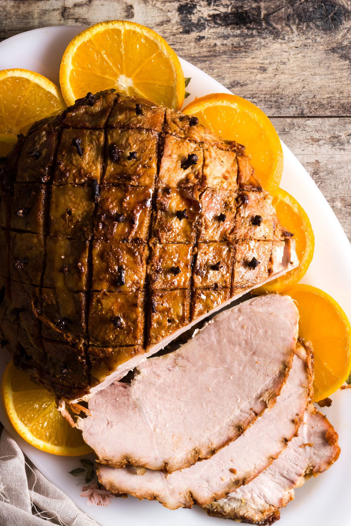 Honey baked ham and orange slices on an oval platter.