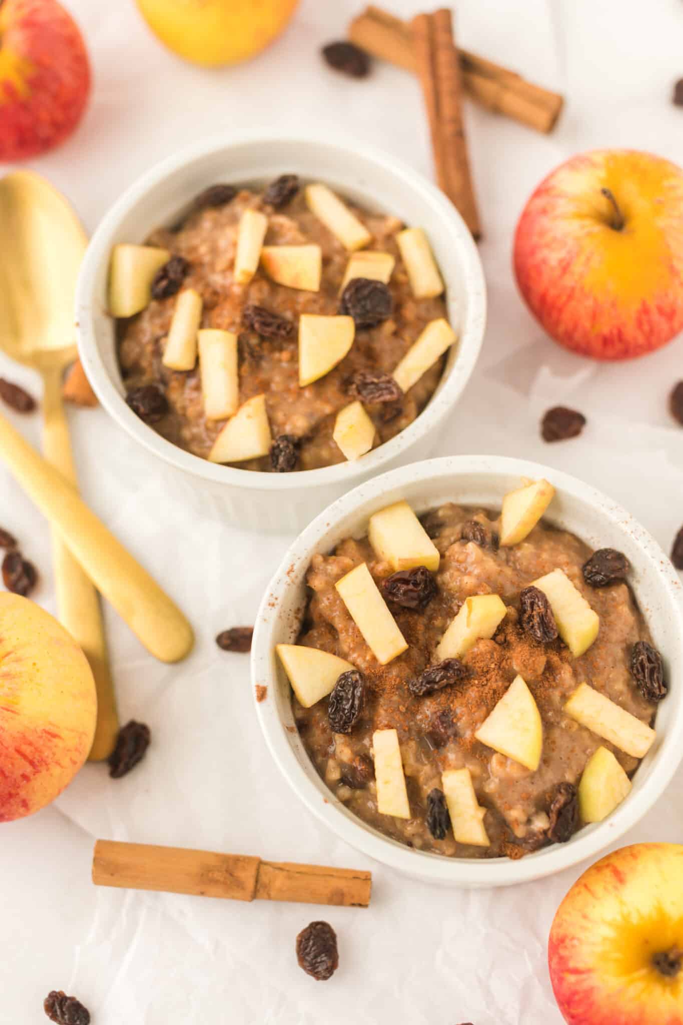 two bowls with instant pot steel cut oats topped with apple and raisins.