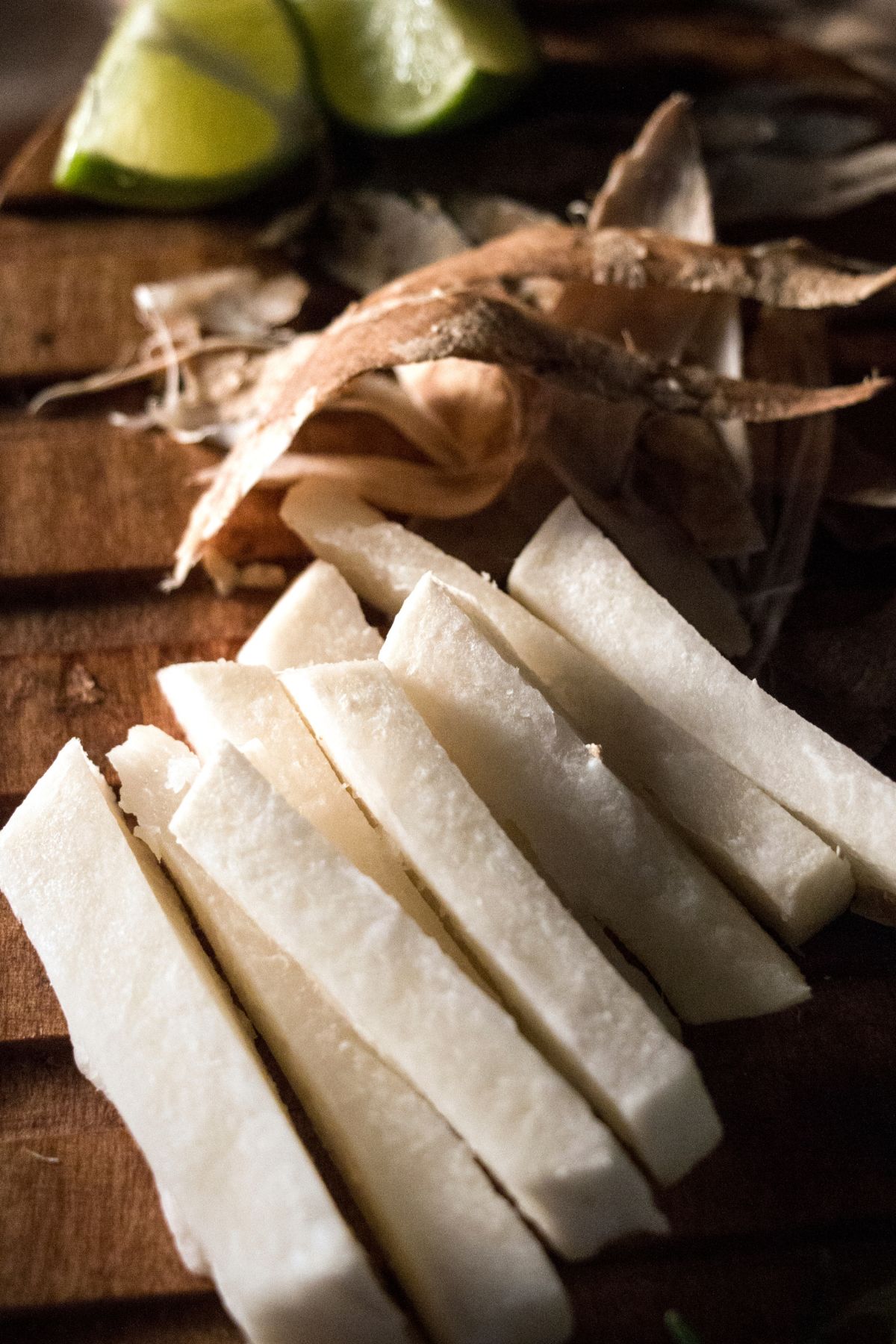 Peeled and sliced jicama on wooden surface.