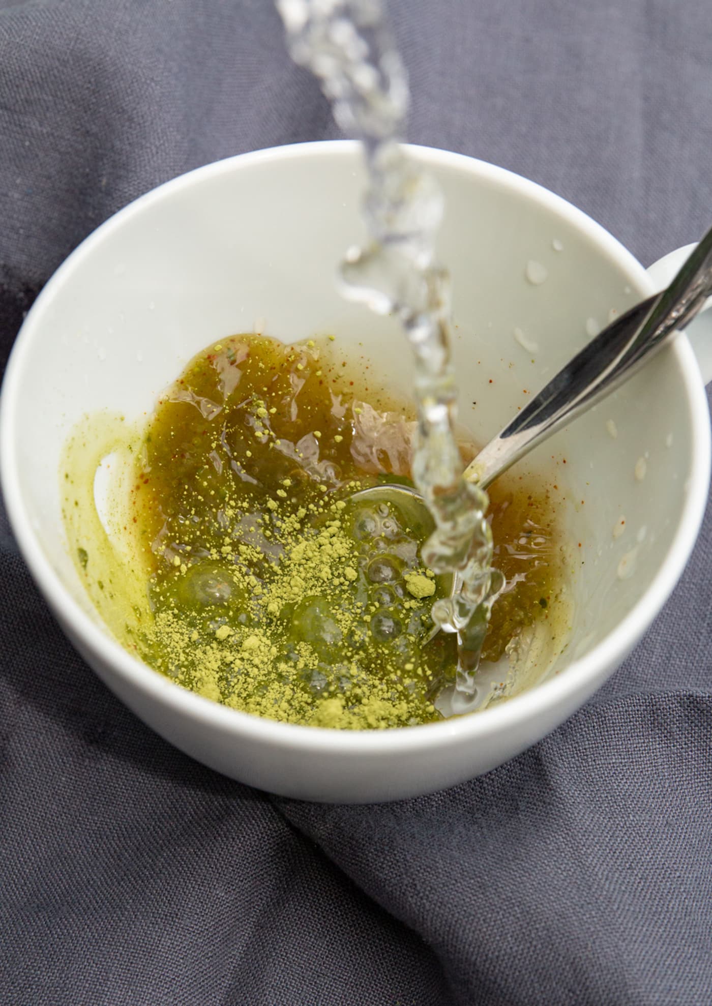 pouring hot water into ingredients to make coconut matcha latte.