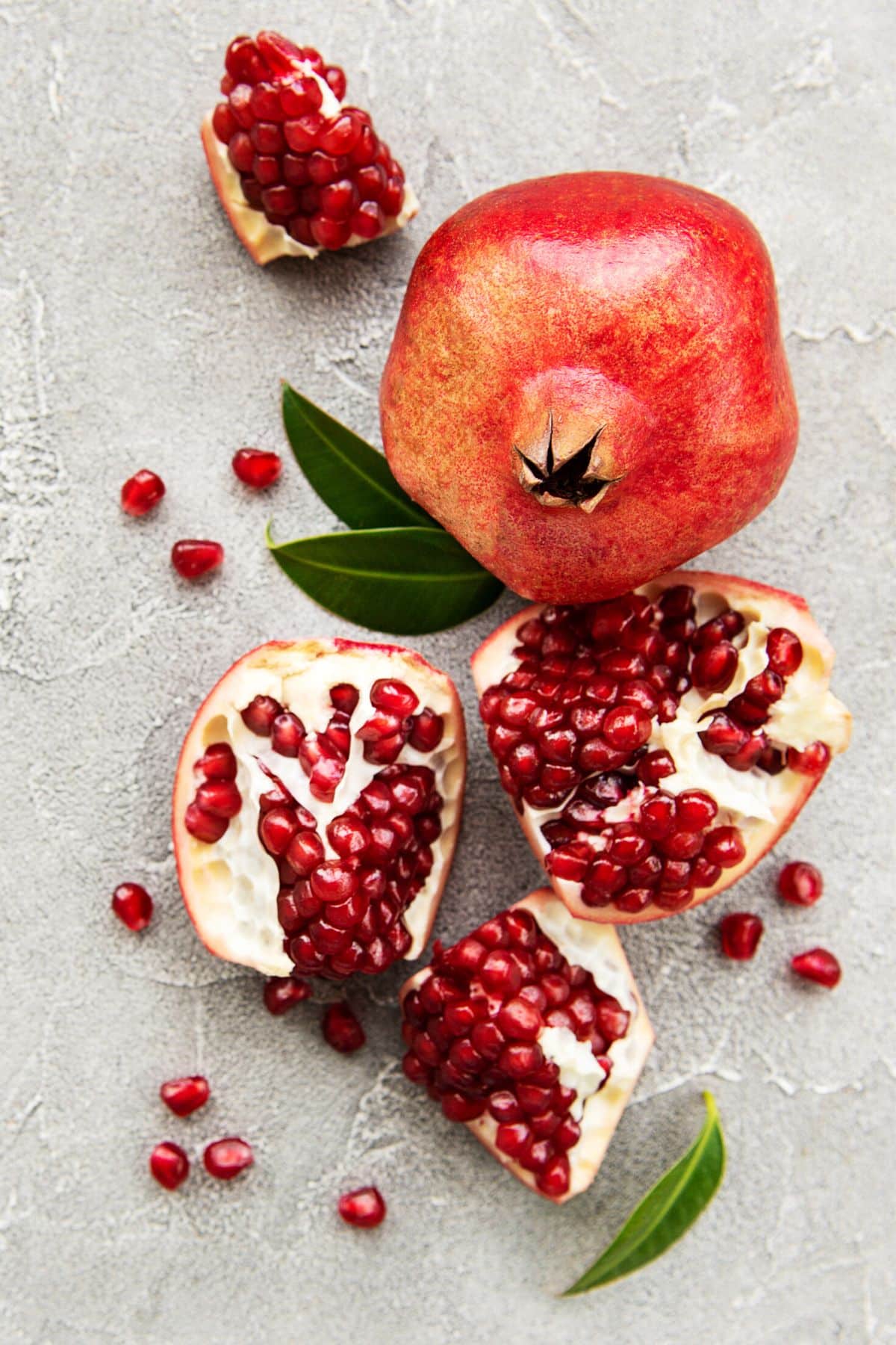 A whole pomegranate next to one that has been sectioned.