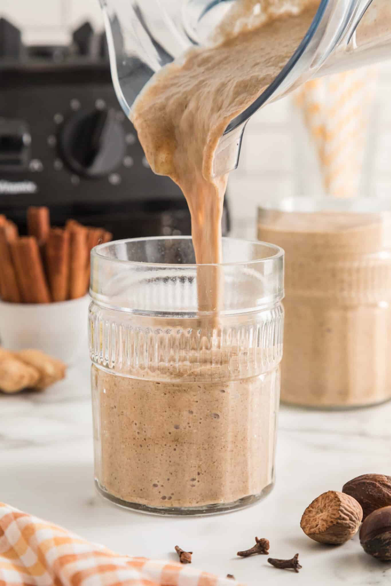 A blender jar pouring gingerbread smoothie into a glass.