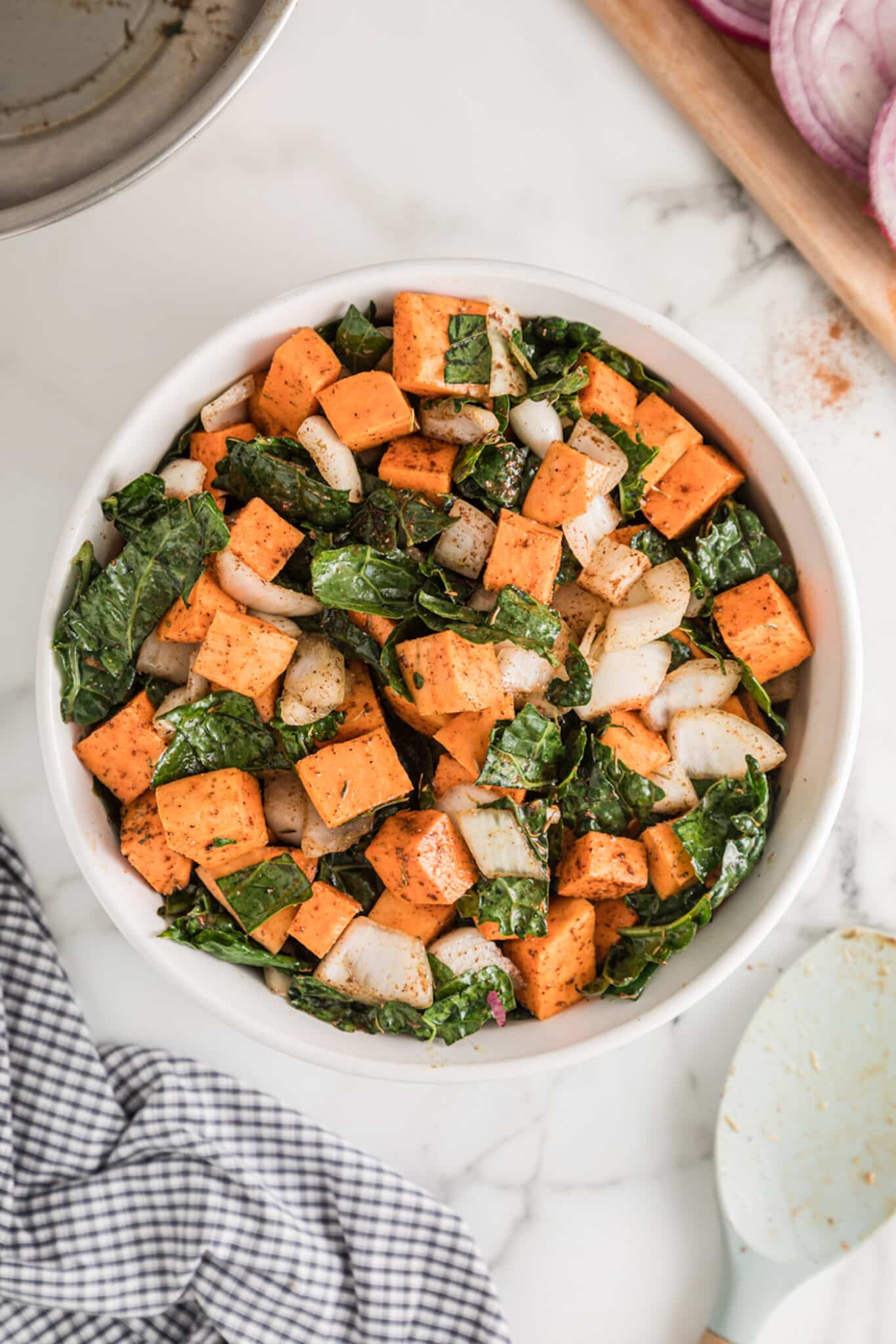 Large white ceramic bowl filled with baked kale and sweet potato.