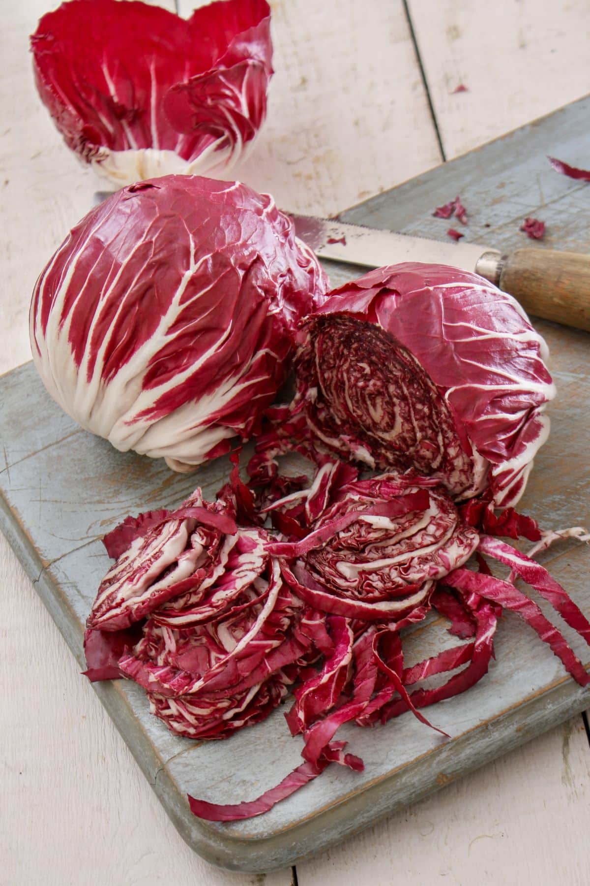 Halved and whole radicchio on wooden cutting board.