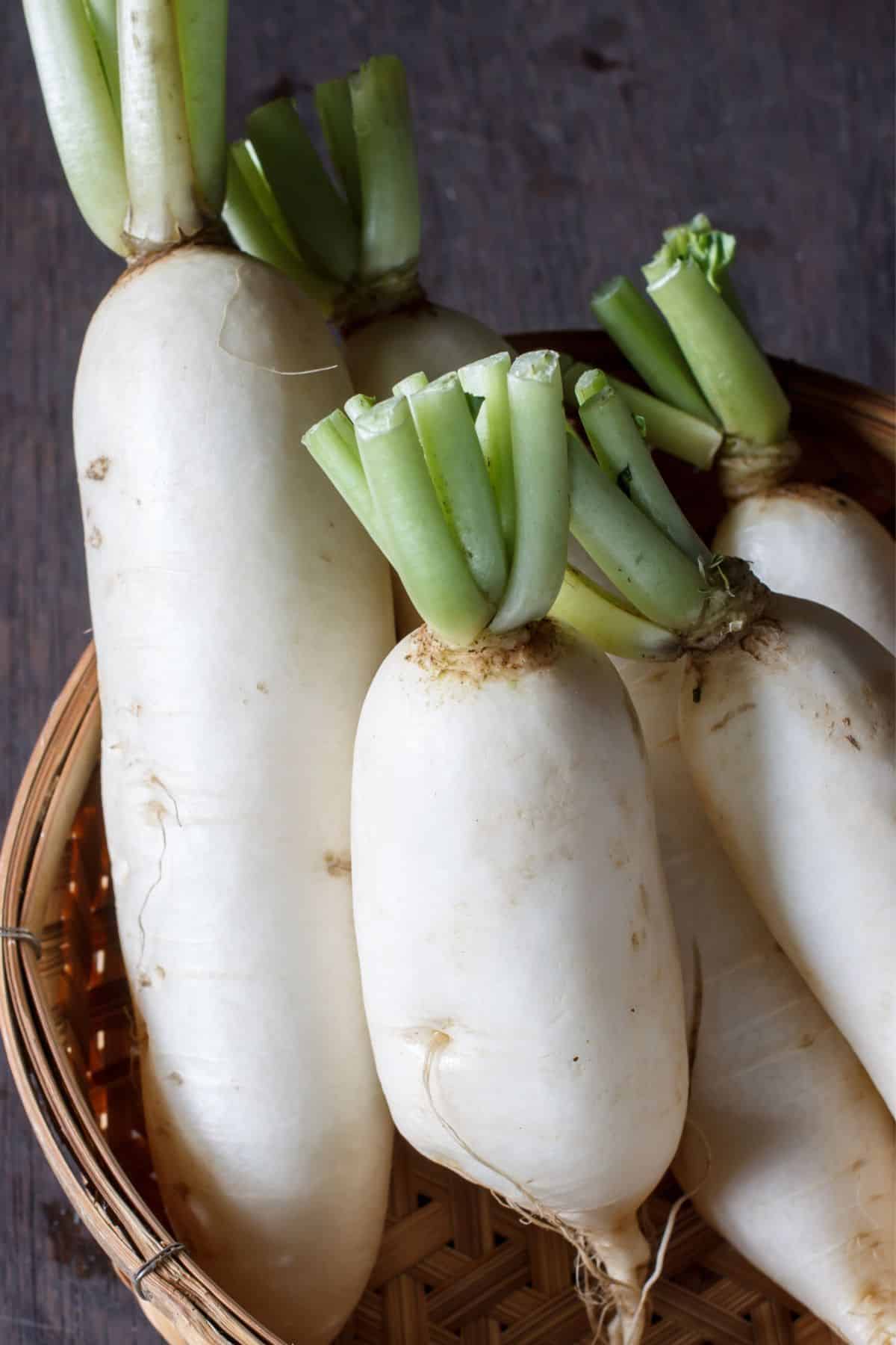 Basket of daikon radish on wooden surface.