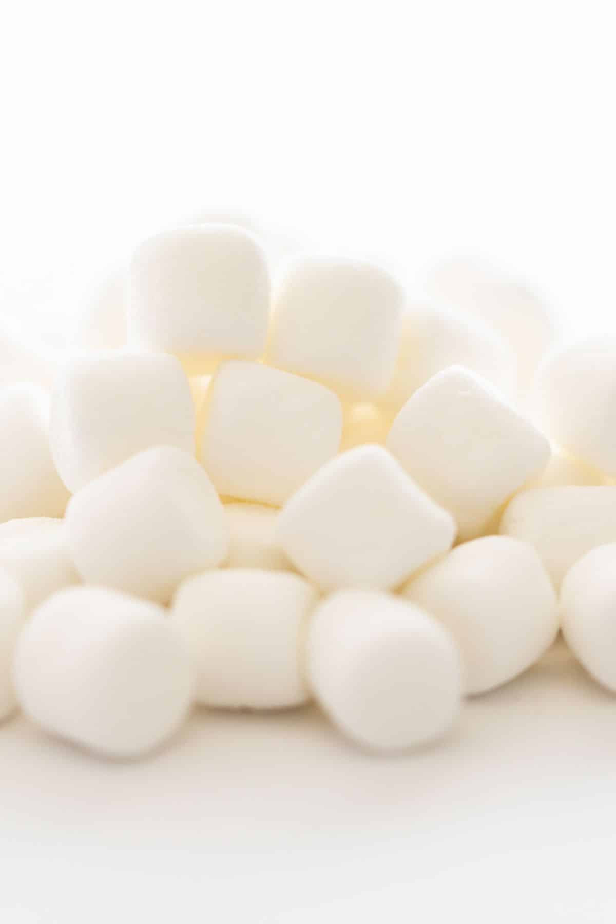 A pile of regular marshmallows on a white background.