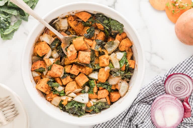 Large white ceramic bowl filled with baked sweet potato and kale.