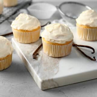 Vanilla cupcakes on a white marble surface.