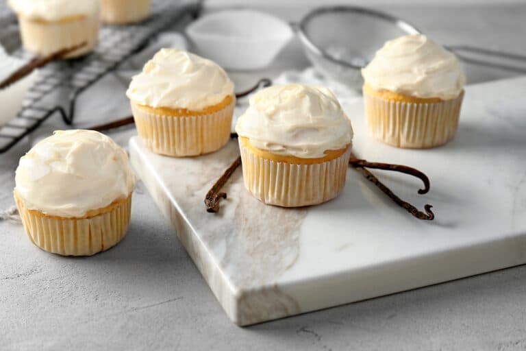 Vanilla cupcakes on a white marble surface.