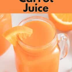 Carrot orange juice in a handled mason jar with an orange slice on the rim.