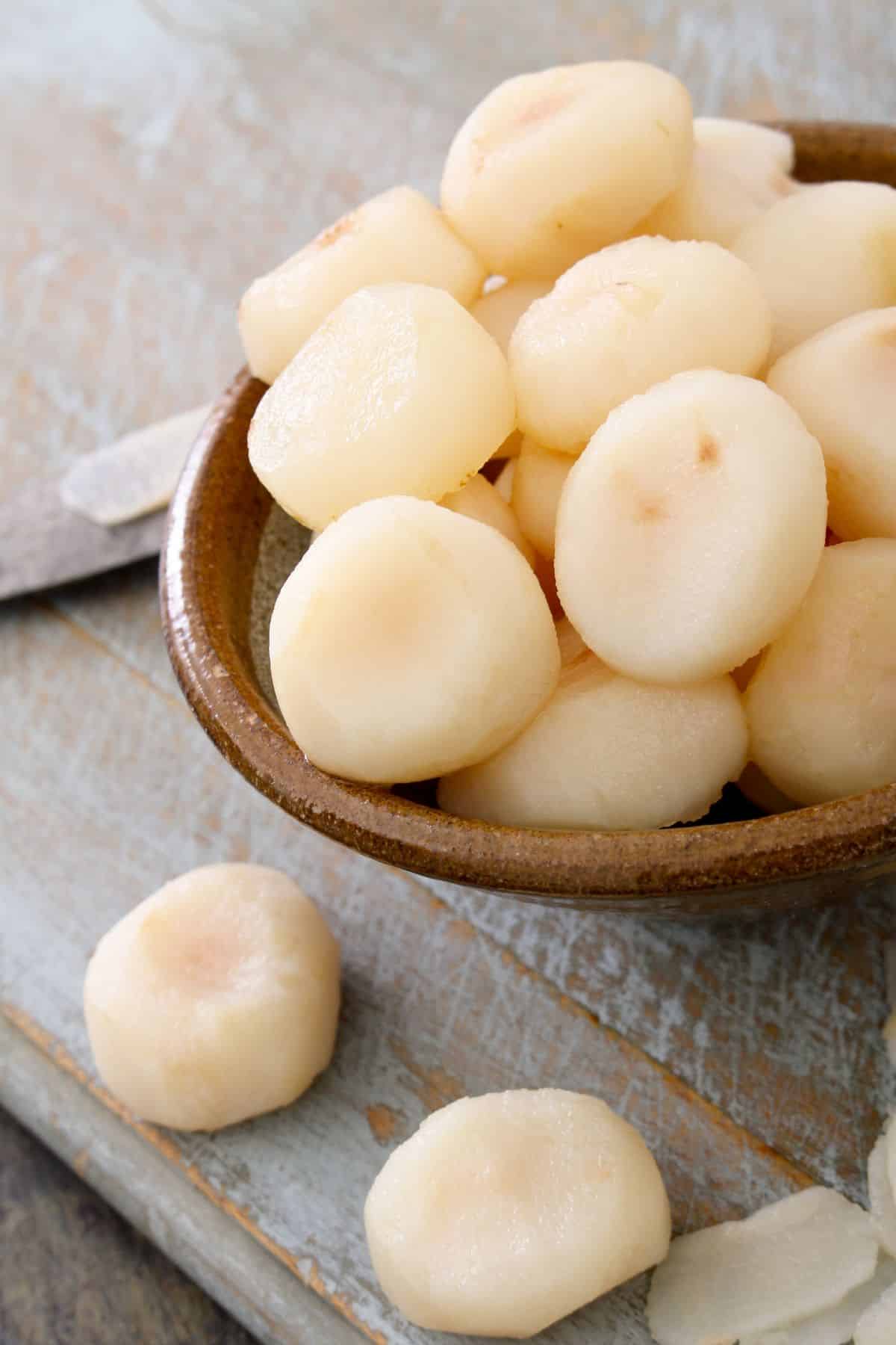 Bowl of water chestnuts on wooden surface.