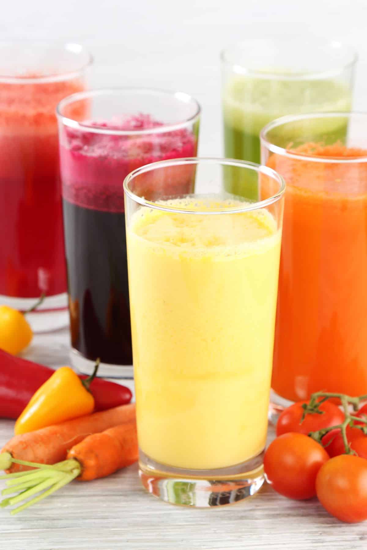 five glasses of different types of juice.