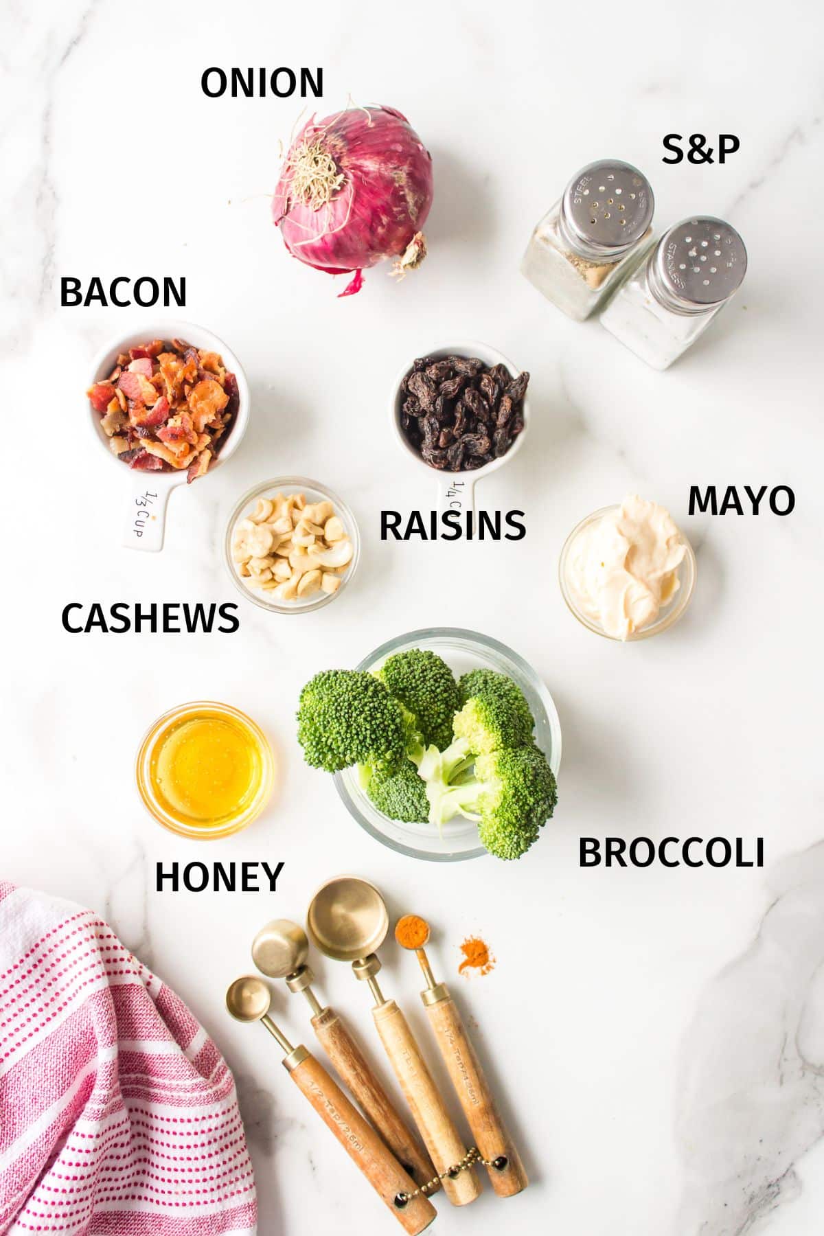 Ingredients to make Whole Foods Broccoli Salad in small bowls on a white surface.