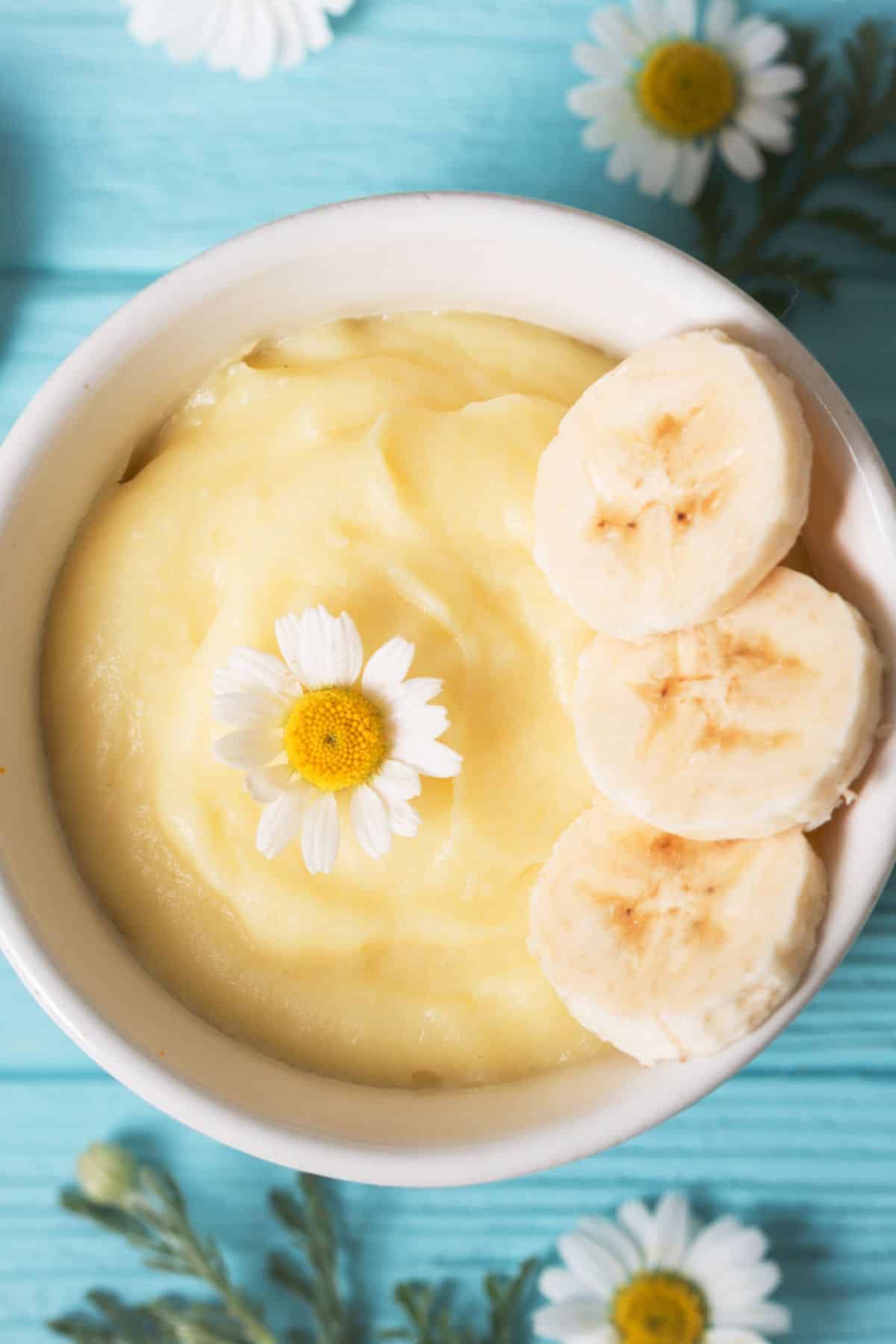 A small white bowl with banana pudding topped with sliced banana.
