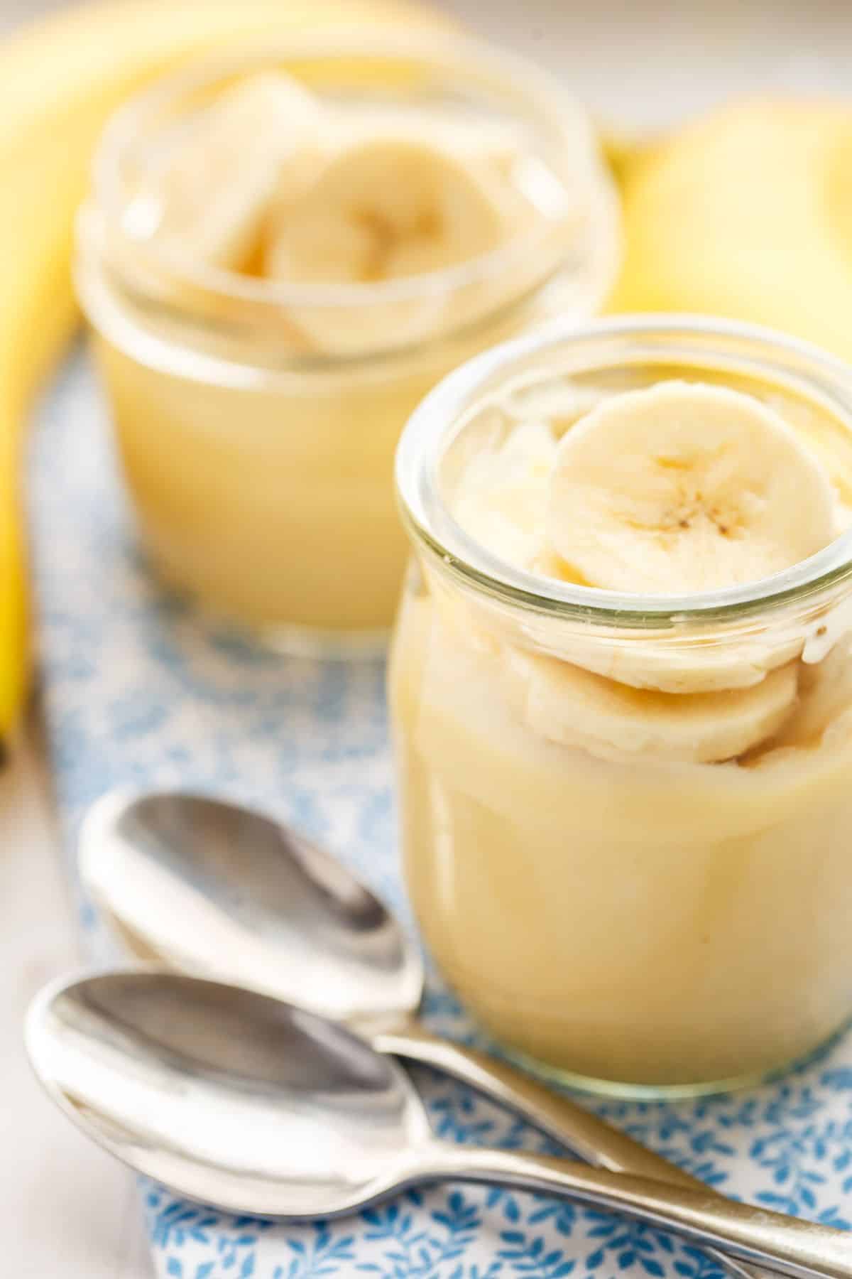 Dairy-free banana pudding in small jars on a striped towel.