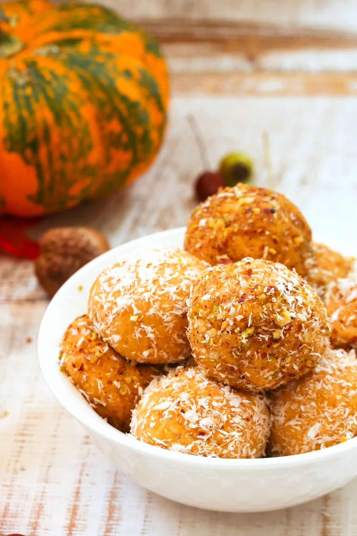 up close photo of orange pumpkin protein balls in a bowl ready to eat. 
