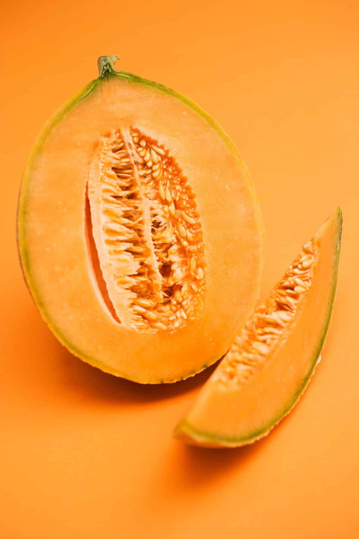 a sliced cantaloupe on an orange background.