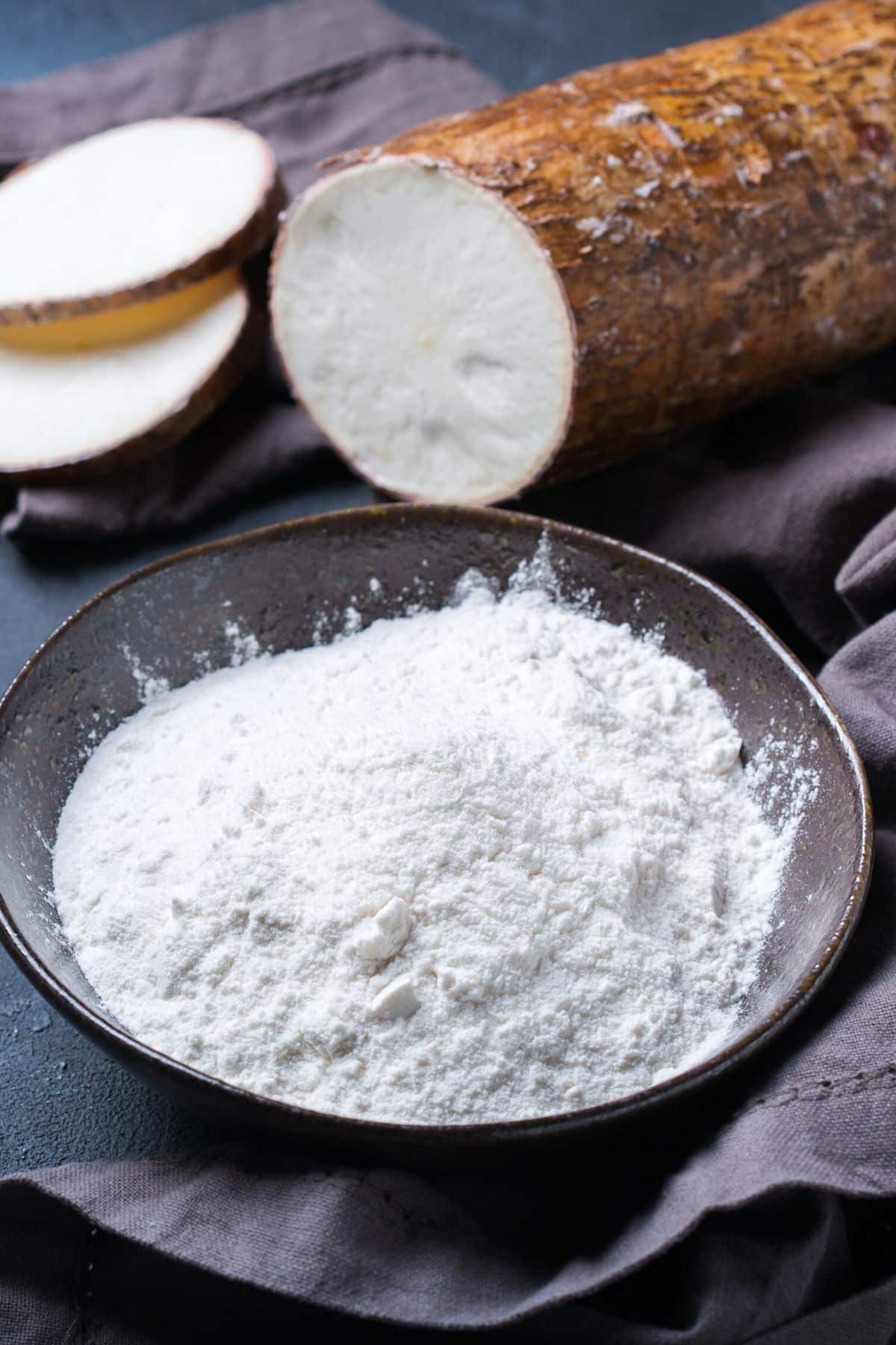 Cassava root next to a bowl of tapioca starch.