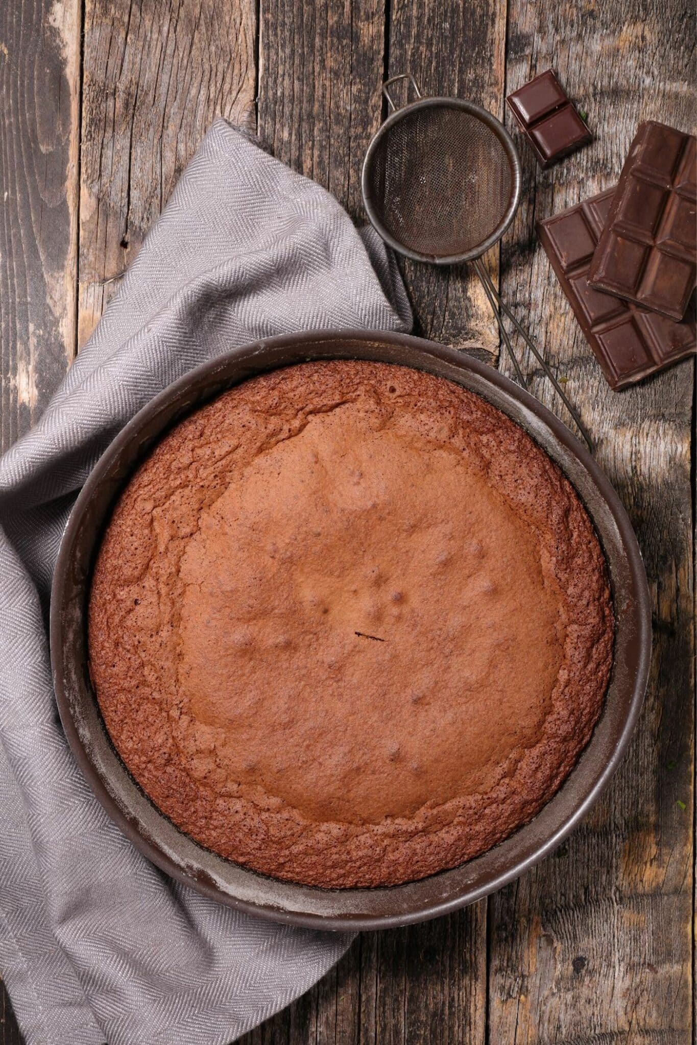 A baked chocolate cake in a round metal cake pan.
