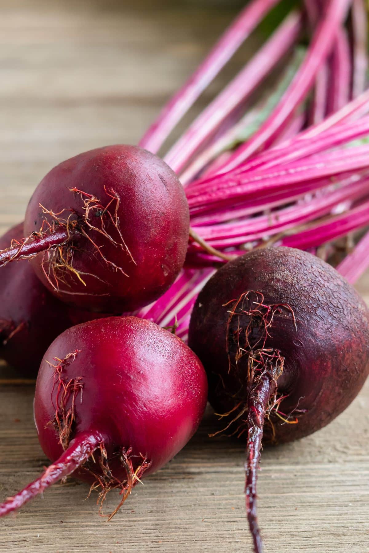 Fresh beets on a wooden cutting board.