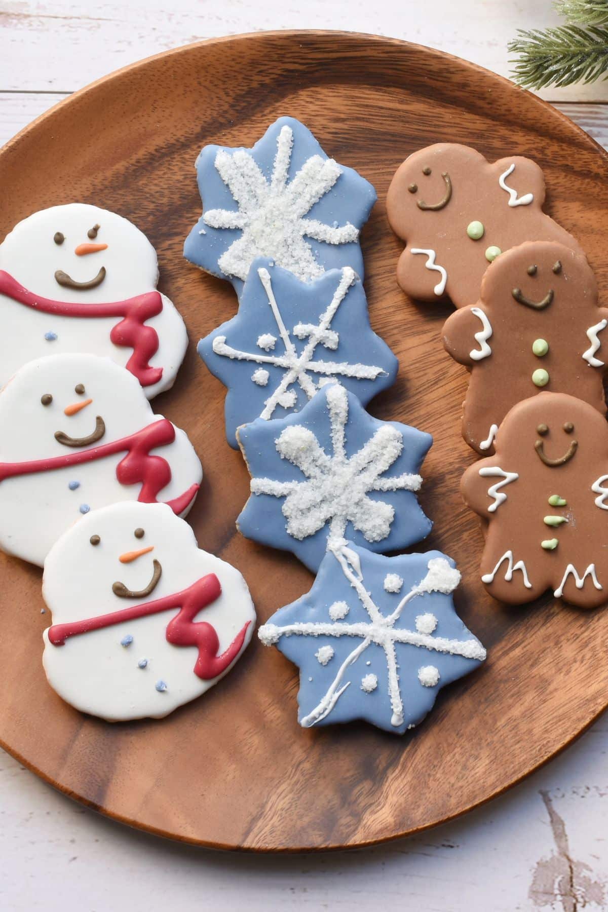 a plate of snowflake, snowman, and gingerbread man cookies.