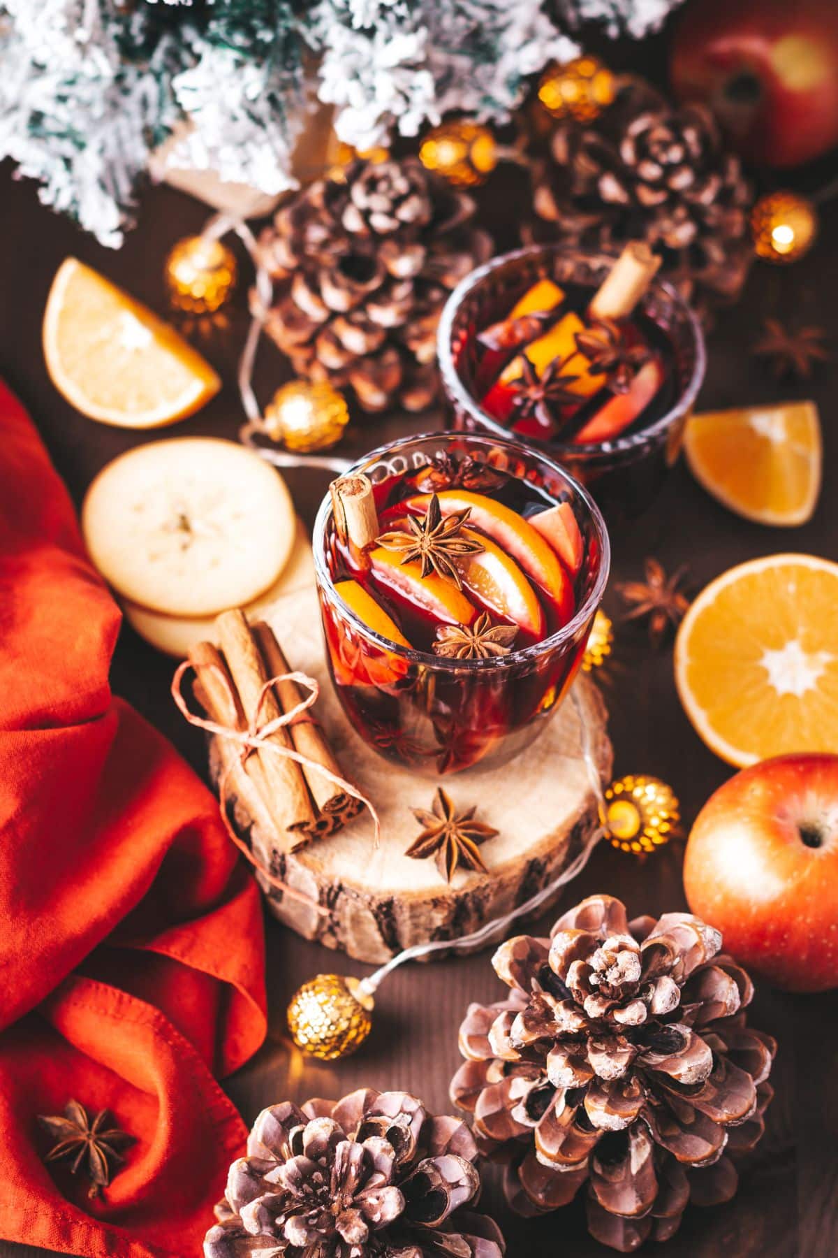 two drinks around a table full of oranges and cinnamon sticks.