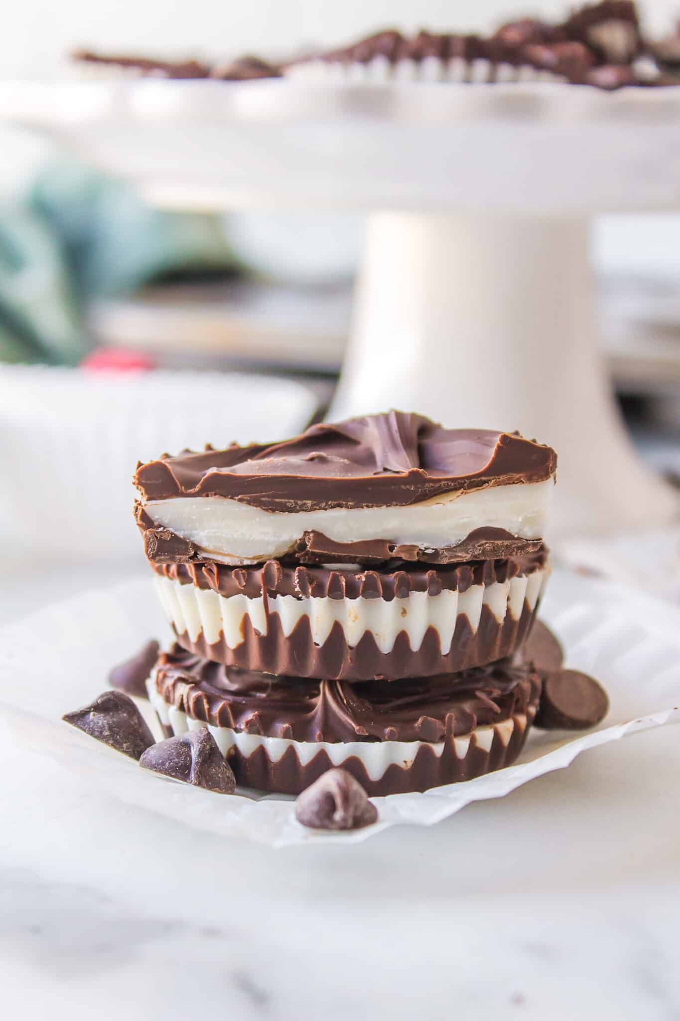 Three homemade peppermint patties stacked on a white plate.