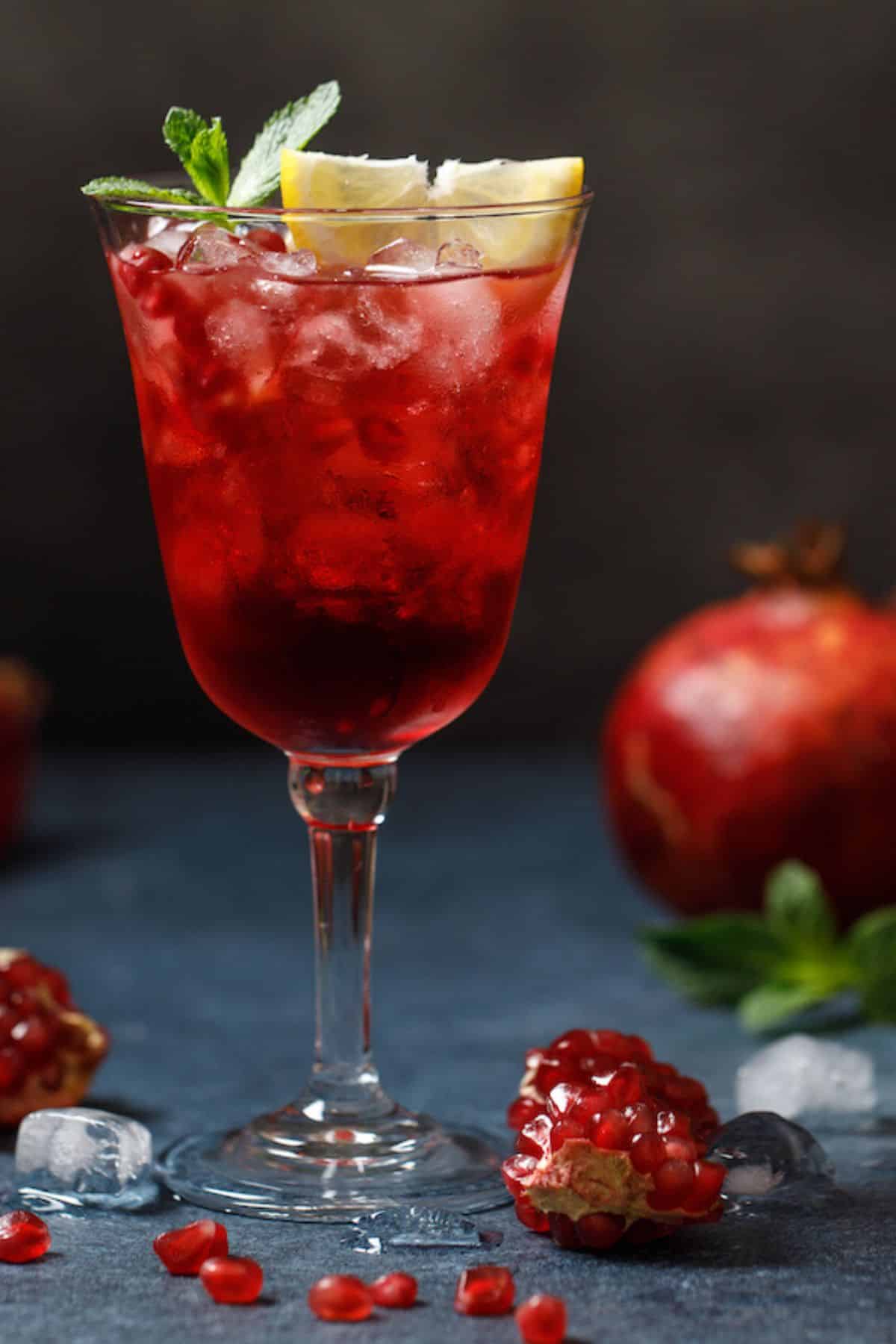pretty glass with pomegranate mocktail served with a slice of lemon.