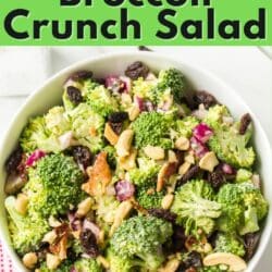 Broccoli crunch salad with raisins and cashews in a white bowl.
