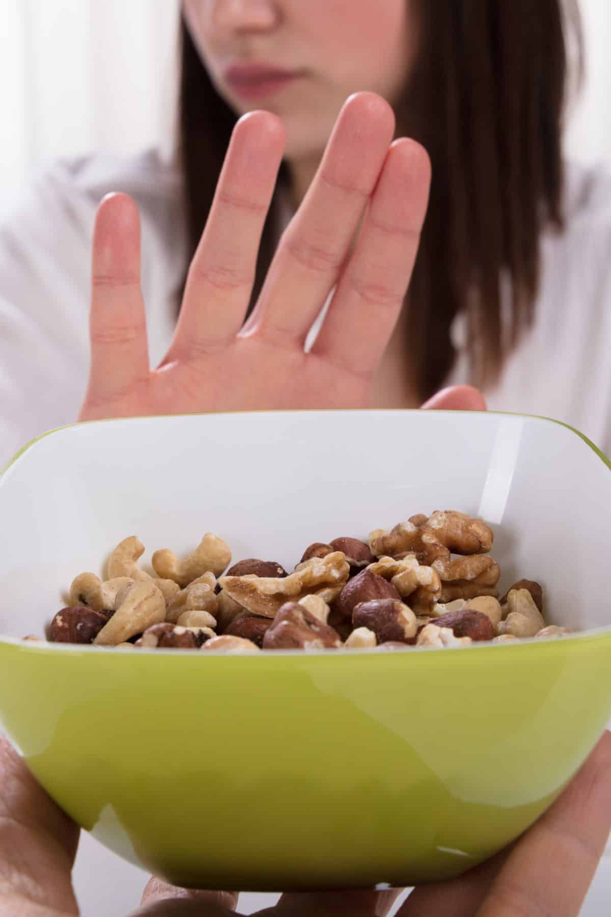 a woman saying no to a bowl of nuts.