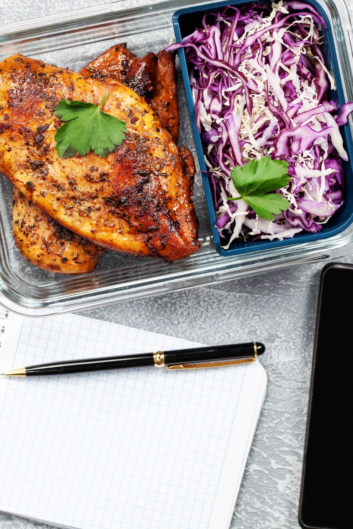 a pen and notepad next to a prepared meal.