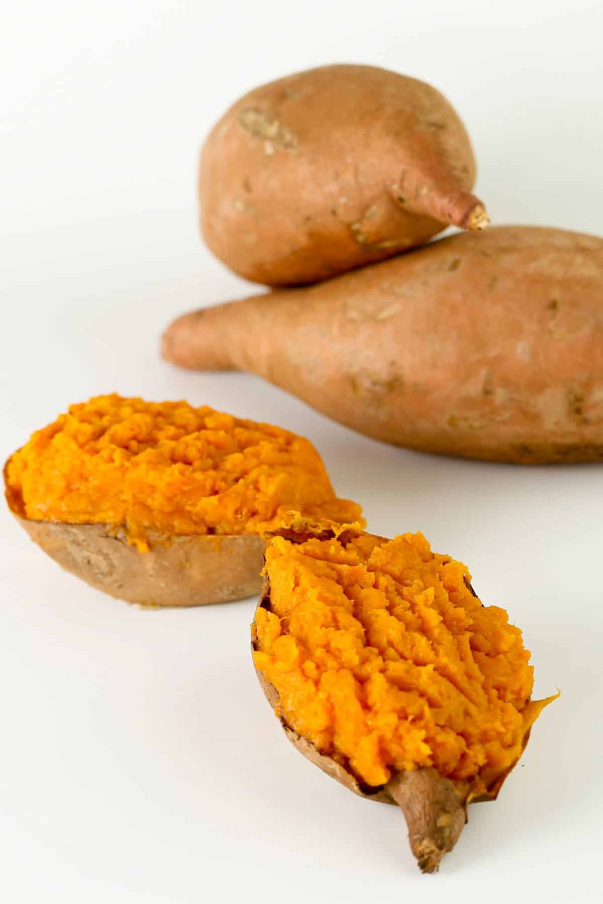 baked sweet potatoes cut in half on table.