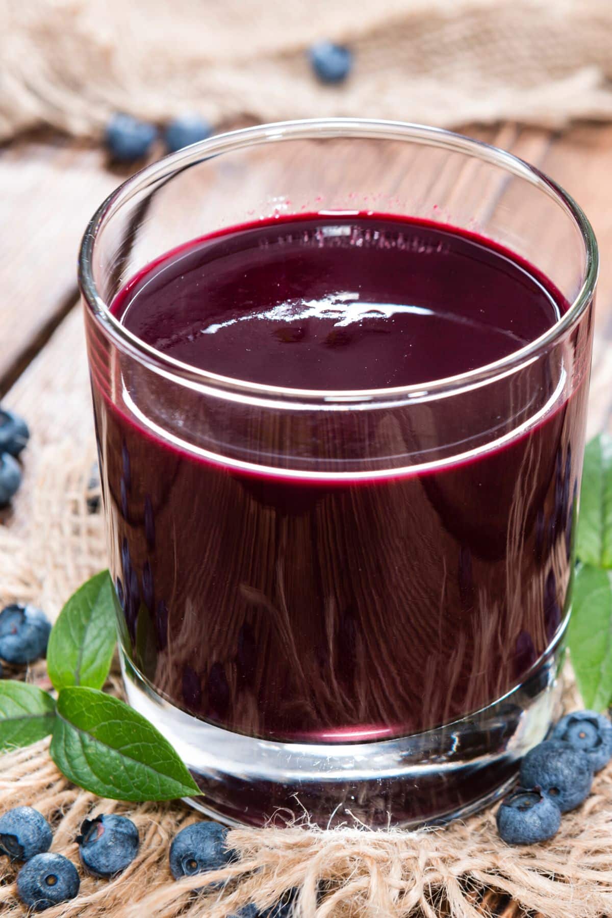 A short glass of blueberry juice on a wooden table.