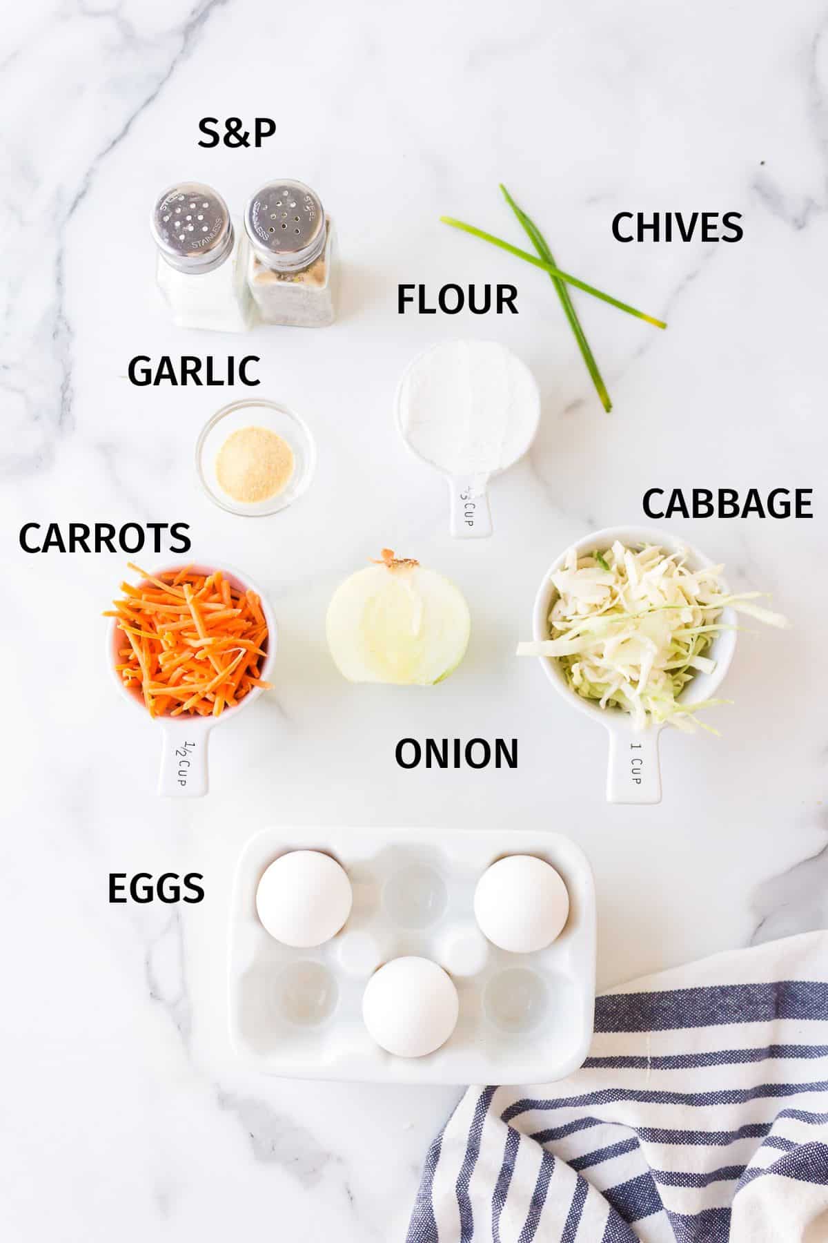 Ingredients to make cabbage fritters in small bowls on a white surface.