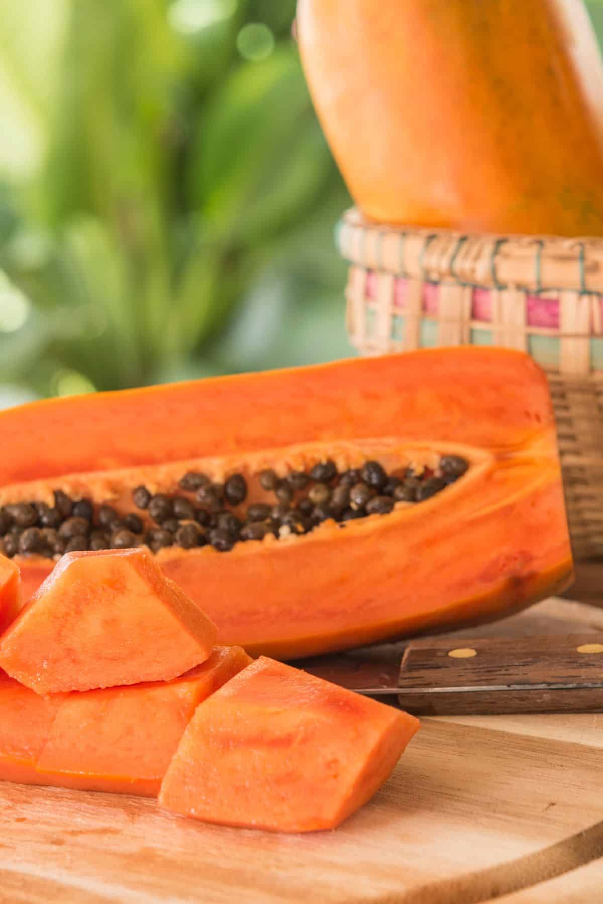 A freshly sliced papaya on a wooden cutting board.