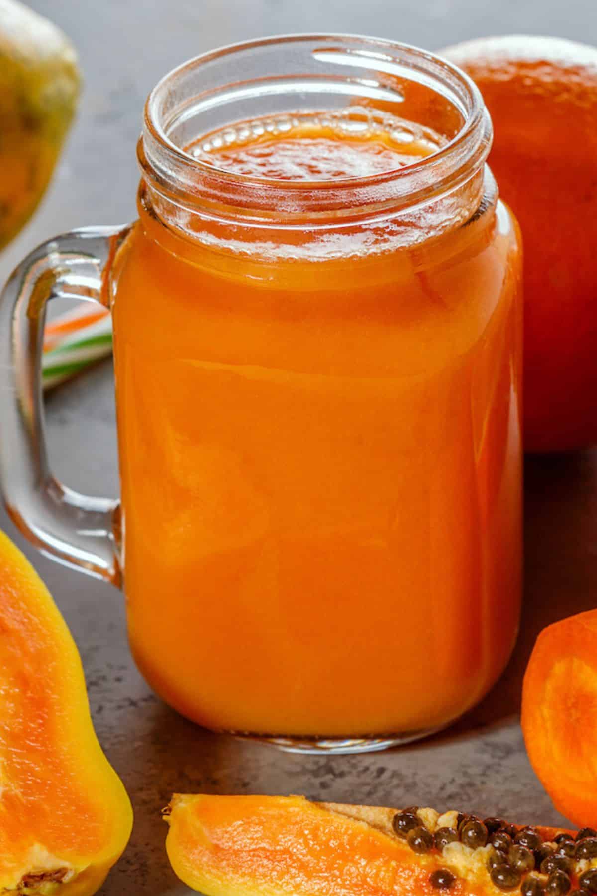 A large handled mason jar filled with papaya juice.