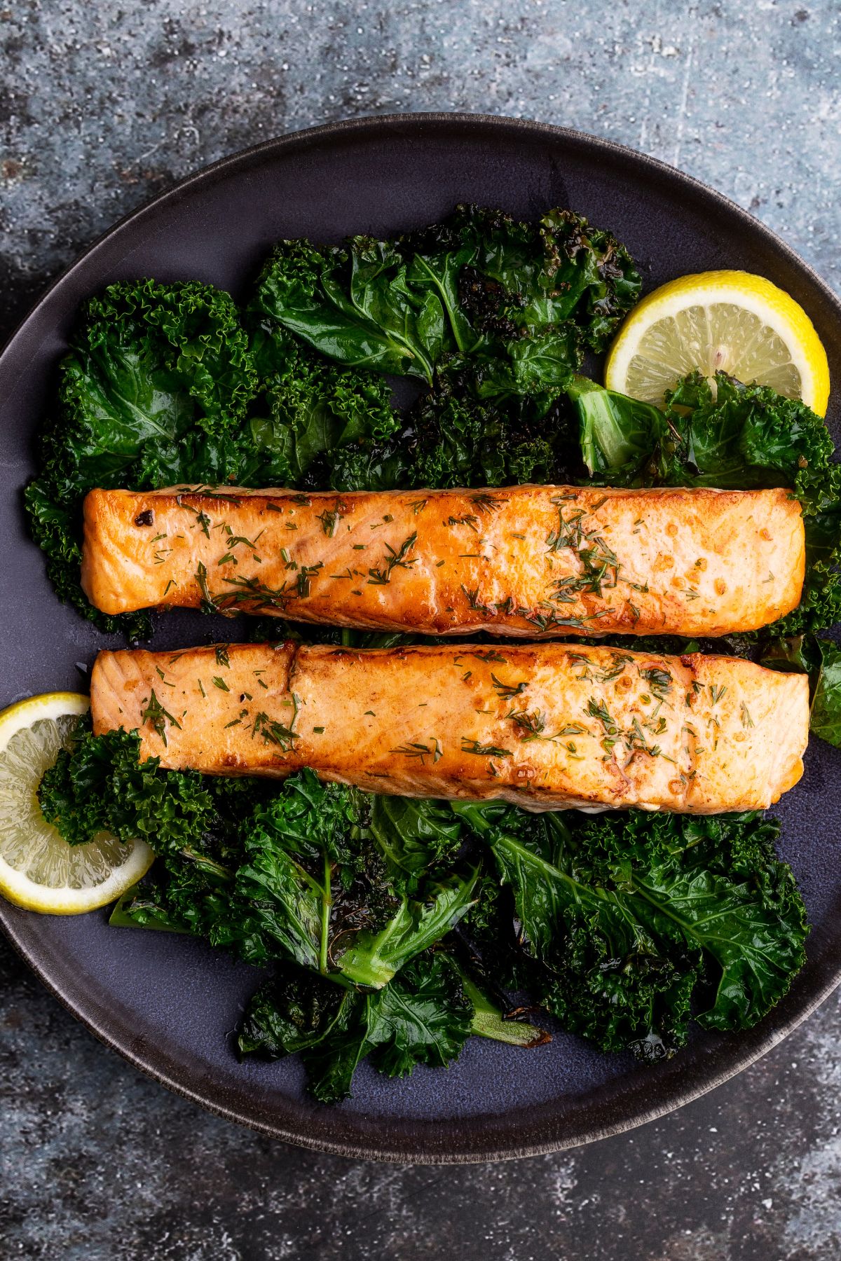a plate of salmon and kale garnished with lemon.