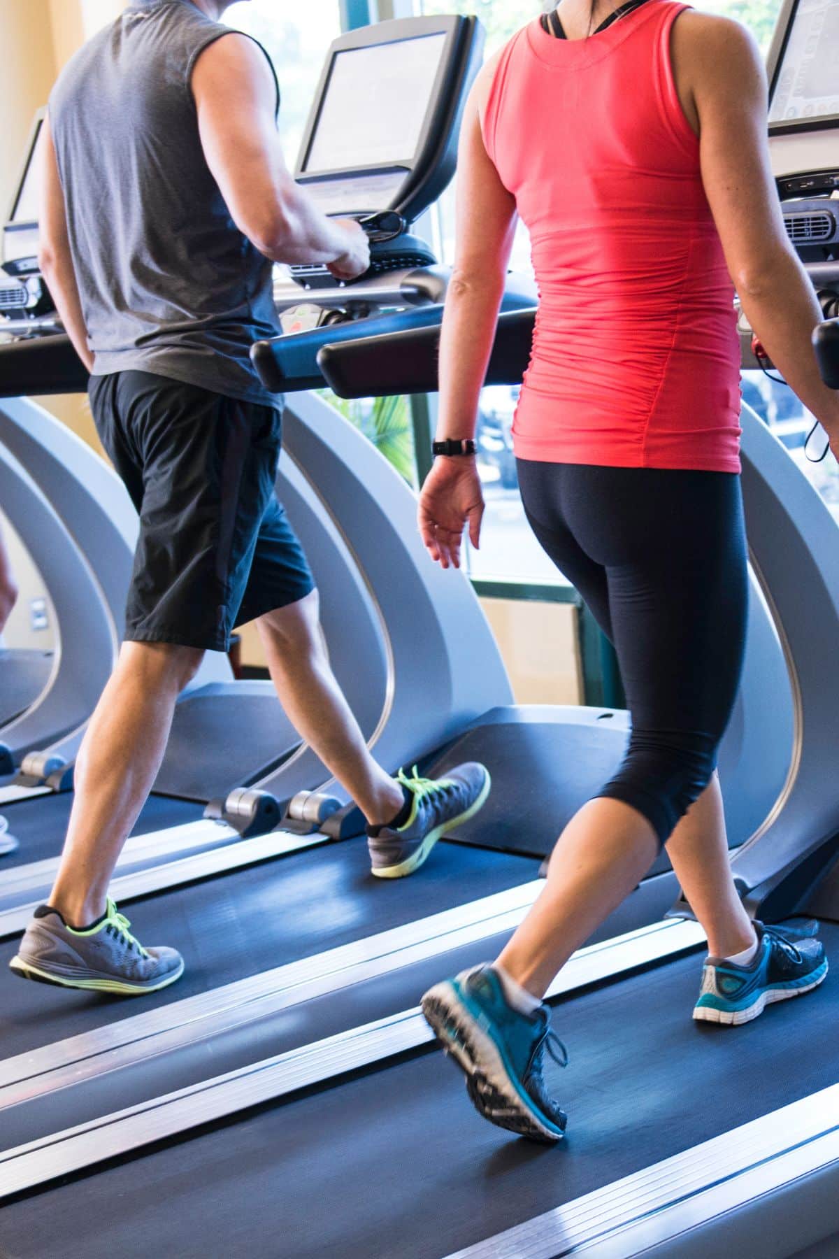 a man and a woman walking on treadmills.