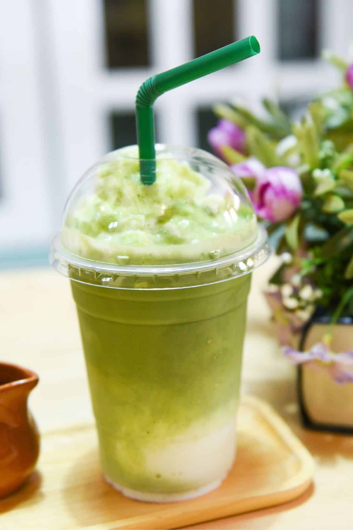 a plastic cup of Matcha Green Tea crème Frappuccino with a green straw.