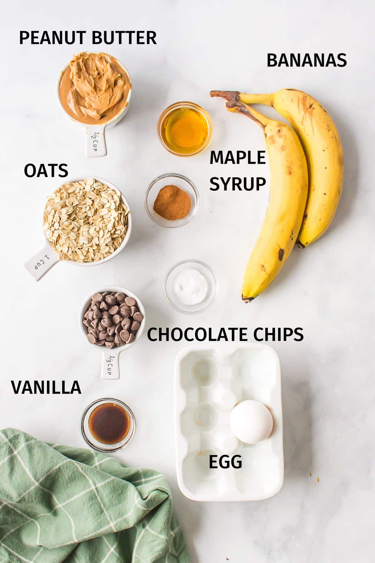 Ingredients to make banana oat bars in bowls on a white surface.