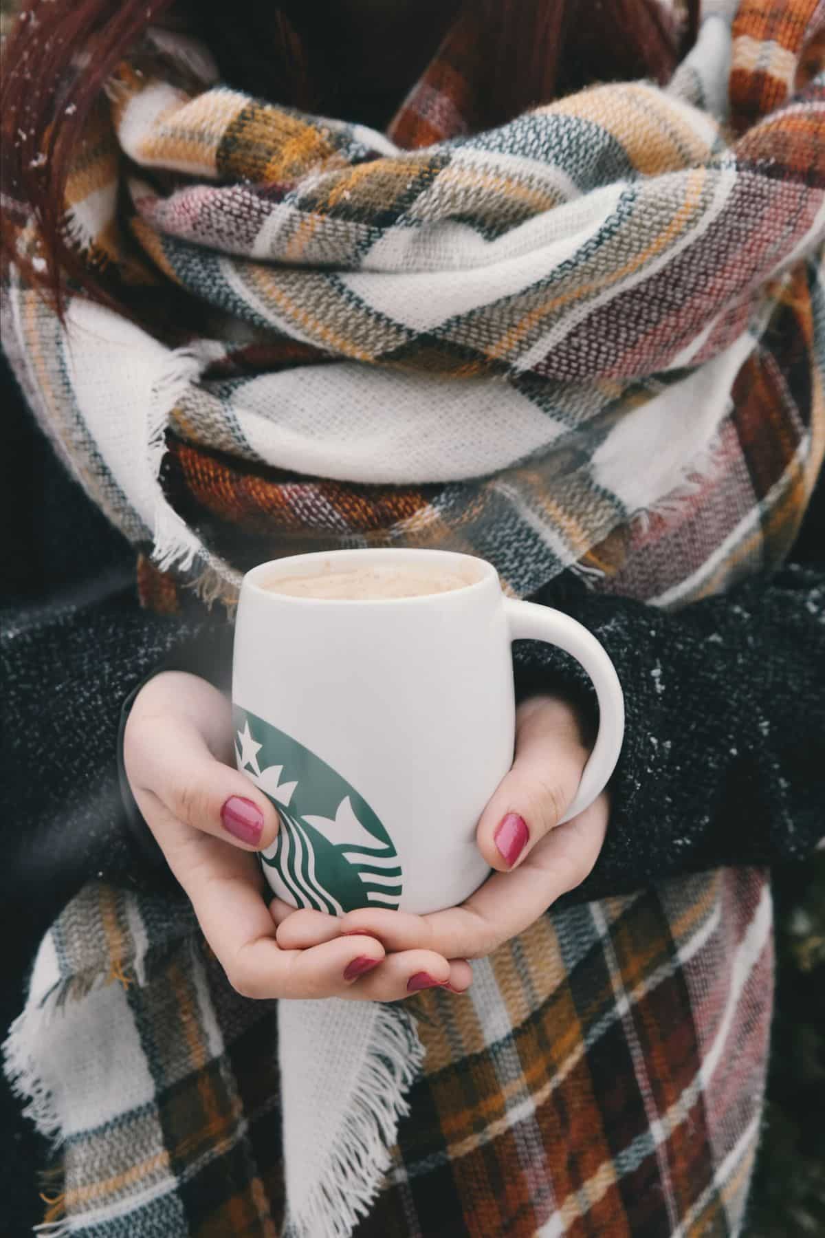 a woman holding a mug of white hot chocolate.