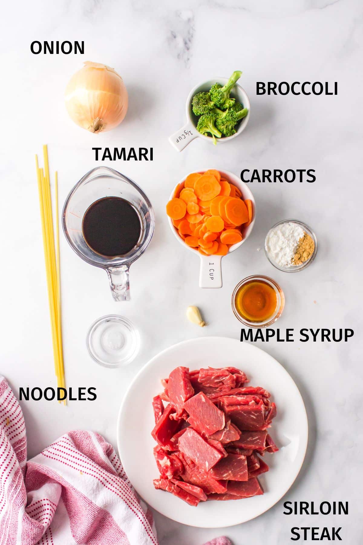 Ingredients for teriyaki beef noodle bowls on a white surface.