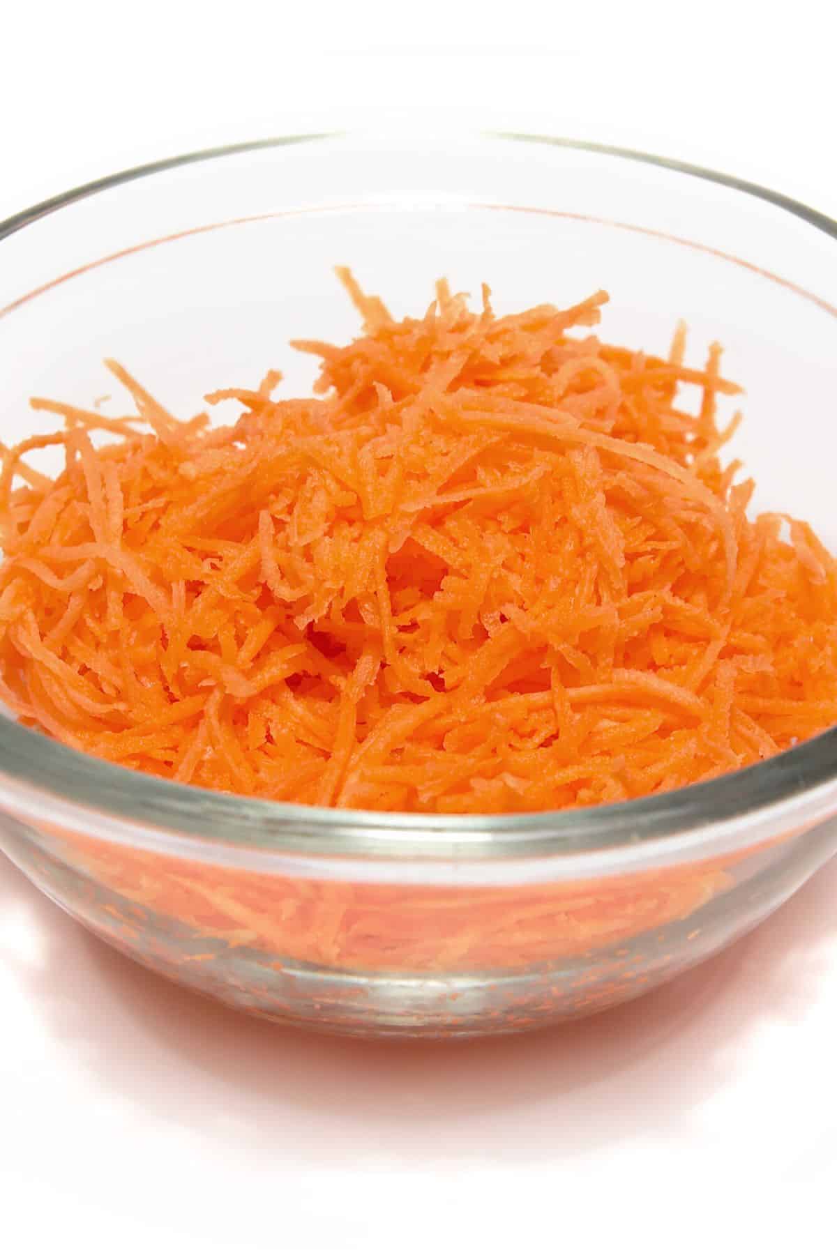 A small glass bowl of freshly grated carrot.