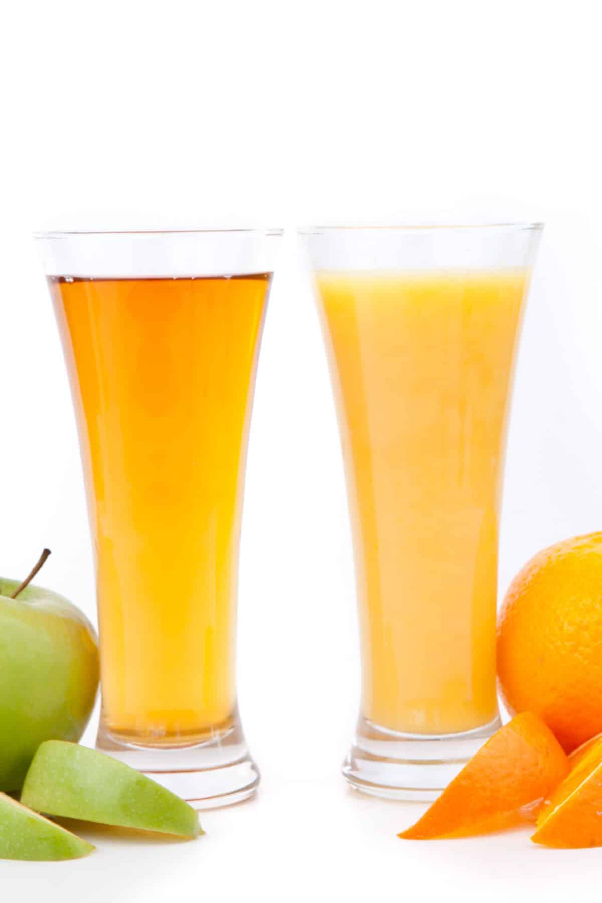 Two tall glasses, one of orange juice and one of apple juice.