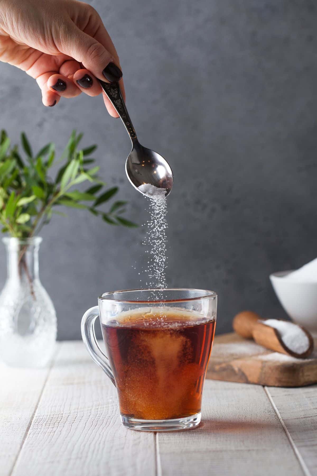 hand pouring sweetener into a hot drink.