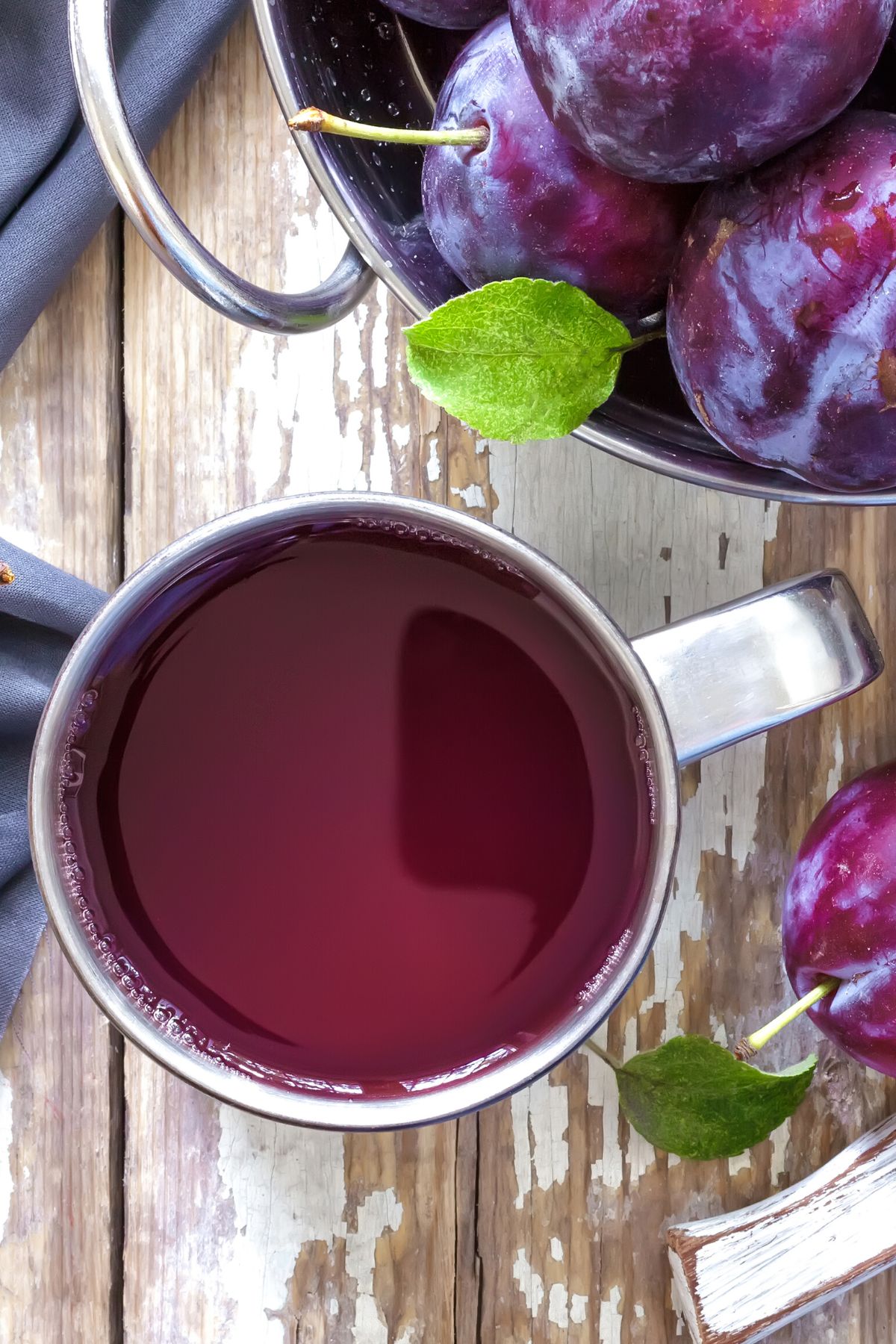 Top view of a silver mug filled with fresh plum juice.